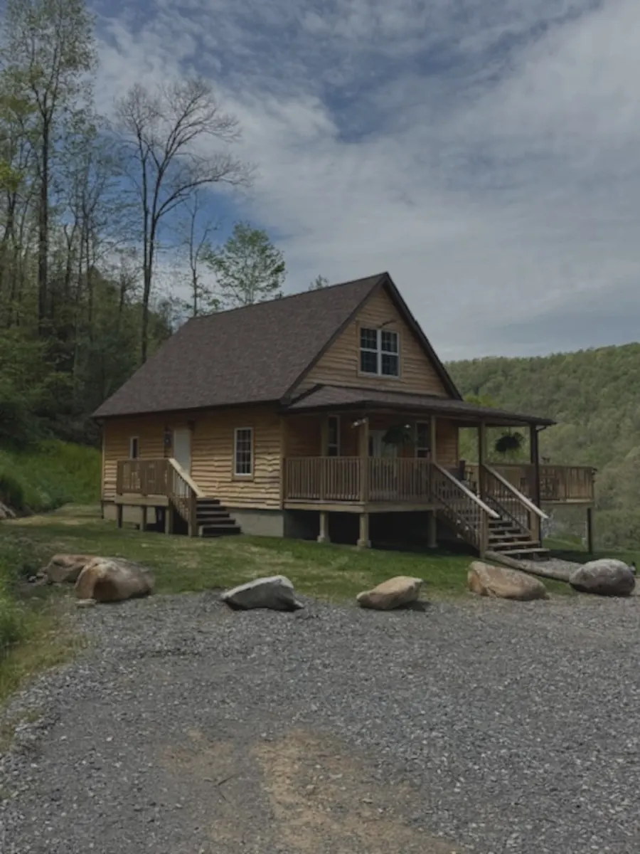 Before: a phone photo of a log cabin taken from the gravel driveway