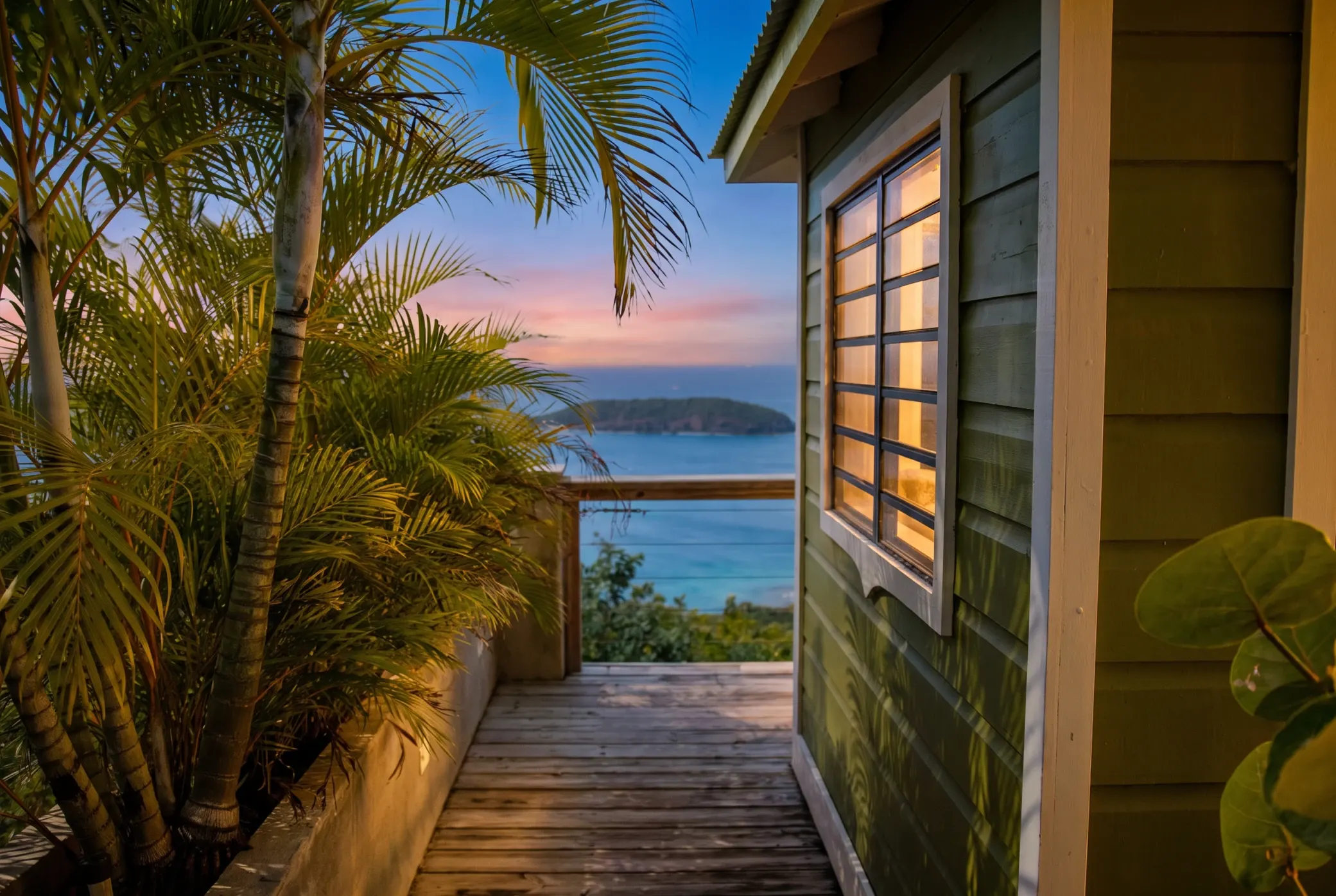 The same walkway at sunset, the cottage window glowing over the water